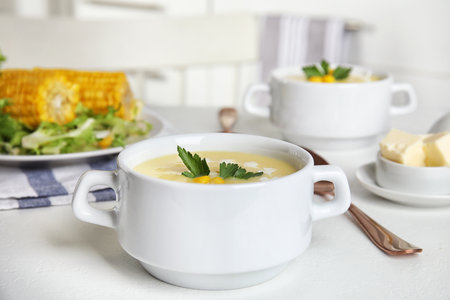 Delicious corn cream soup served on white table indoorsの写真素材