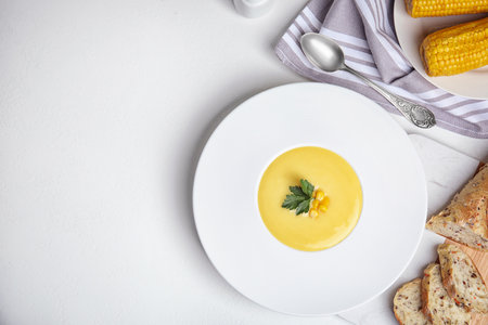 Delicious corn cream soup served on white table, flat lay. Space for textの写真素材