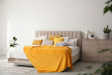 Stylish bedroom interior with soft yellow pillows and blanketの写真素材