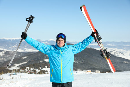 Happy man with ski equipment in mountains. Winter vacation