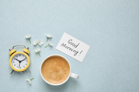 Flat lay composition with message GOOD MORNING and coffee on light blue background. Space for textの写真素材