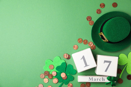 Flat lay composition with wooden block calendar on green background, space for text. St. Patrick's...