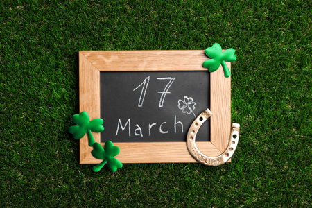 Flat lay composition with horseshoe and chalkboard on grass. St. Patrick's Day celebration