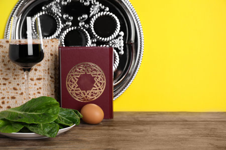 Symbolic Pesach (Passover Seder) items on wooden table against yellow backgroundの写真素材