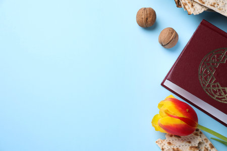 Flat lay composition with symbolic Pesach (Passover Seder) items on light blue background, space for...