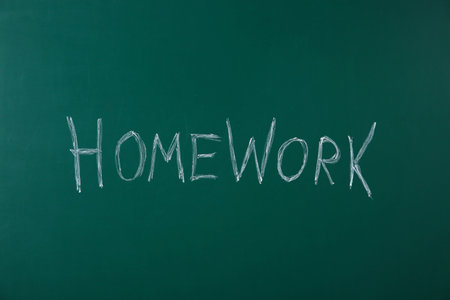 Word HOMEWORK written with chalk on green chalkboardの写真素材