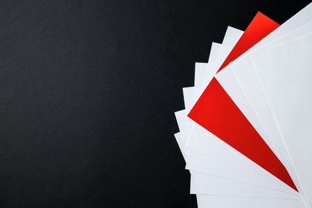 White paper sheets and different one on black background, flat lay. Space for text