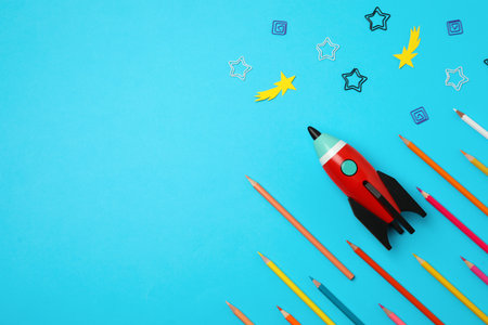 Bright toy rocket and school supplies on light blue background, flat lay. Space for textの写真素材