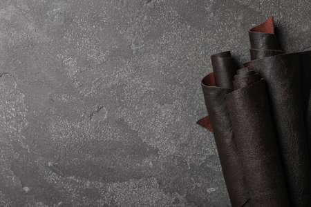 Leather samples on gray stone background, top view. Space for text
