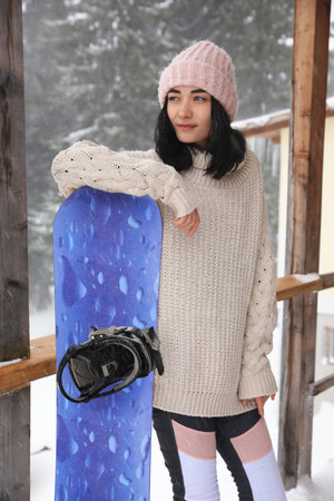 Young woman with snowboard wearing winter sport clothes outdoorsの写真素材