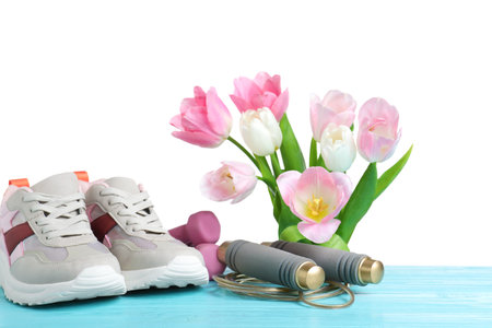 Composition with spring flowers and sports items on light blue wooden table against white backgroundの写真素材