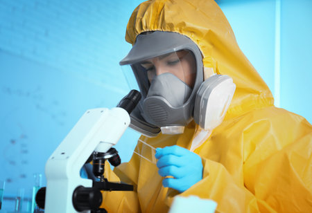 Scientist in chemical protective suit using microscope at laboratory. virus research