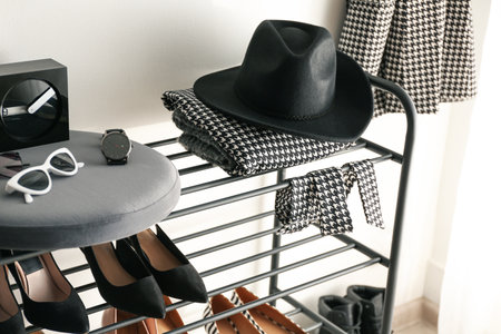 Black shelving unit with shoes and various accessories near white wall in hallの写真素材