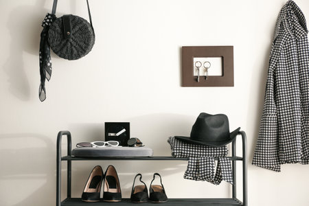 Black shelving unit with shoes and accessories near white wallの写真素材