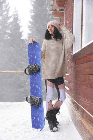 Young woman with snowboard wearing winter sport clothes outdoorsの写真素材