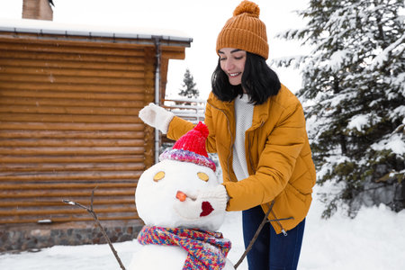 Happy woman making snowman outdoors. winter holidays