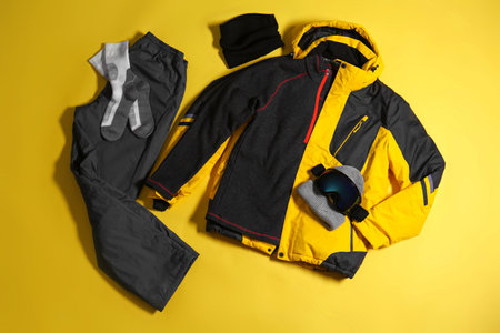 Stylish winter sport clothes on yellow background, flat lay