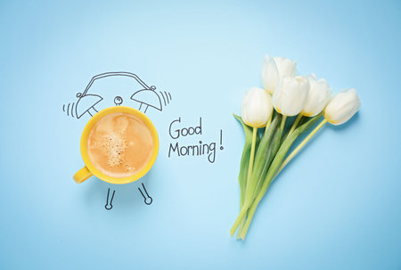 Flat lay composition with good morning wish and aromatic coffee on light blue backgroundの写真素材