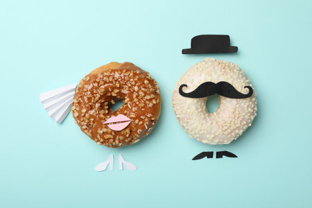 Bride and groom made with donuts on light blue background, flat layの写真素材