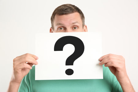 Man holding paper with question mark on white background