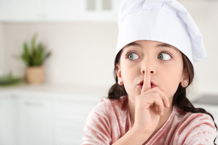 Cute little girl wearing chef's hat in the kitchenの写真素材