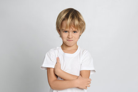 Portrait of cute little boy on light grey background