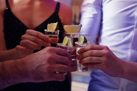 Young people toasting with Mexican Tequila shots in bar, closeupの写真素材