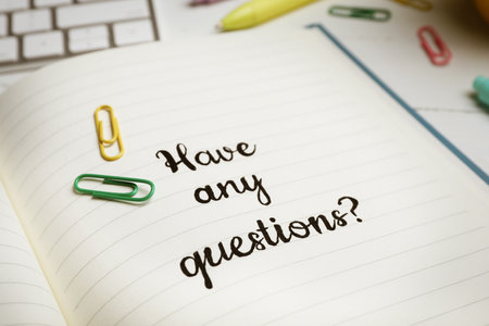 Notebook with phrase HAVE ANY QUESTIONS and stationery on table, closeupの写真素材