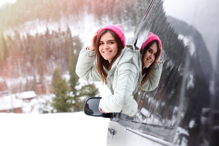 Happy young woman looking out of car window on road. winter holidaysの写真素材