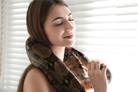 Young woman with boa constrictor at home. Exotic pet