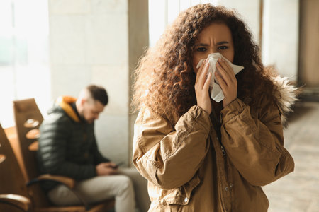 Young African-American woman sneezing indoors. Influenza virusの写真素材