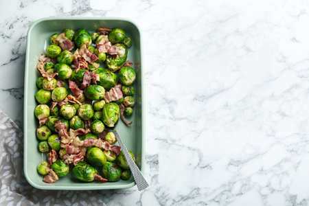 Delicious Brussels sprouts with bacon on white marble table, top view. Space for textの写真素材