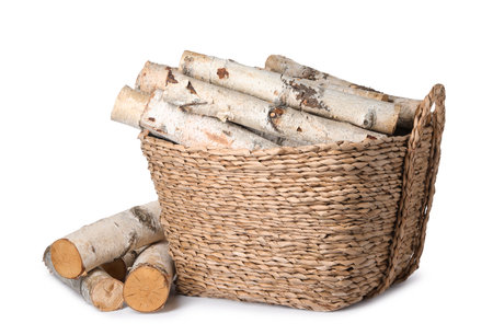 Wicker basket with cut firewood isolated on whiteの写真素材