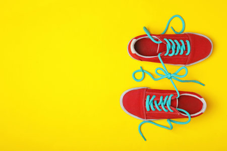 Shoes tied together on yellow background, flat lay with space for text. April Fool's Dayの写真素材