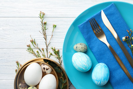Festive Easter table setting with eggs and floral decoration on wooden background, flat layの写真素材