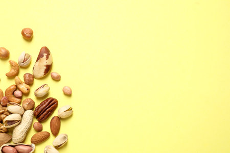 Different delicious nuts on yellow background, flat lay. Space for textの写真素材