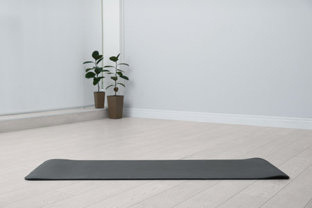 Unrolled black yoga mat on floor in roomの写真素材