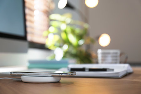 Modern workplace and smartphone charging with wireless padの写真素材