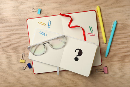 Notebook with question mark and stationery on wooden table, flat layの写真素材