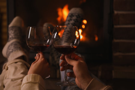 Couple with glasses of red wine near burning fireplace, closeupの写真素材