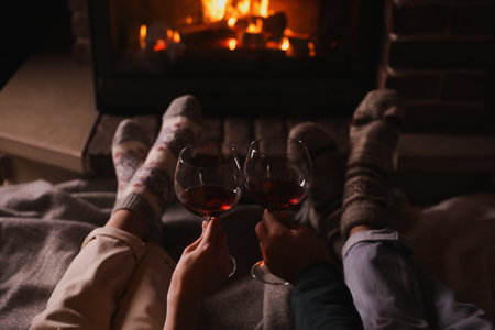 Couple with glasses of red wine near burning fireplace, closeupの写真素材