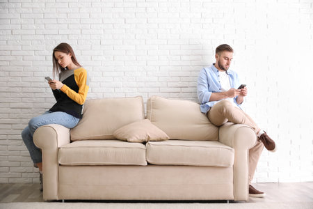 Couple addicted to smartphones ignoring each other at home. relationship problemsの写真素材