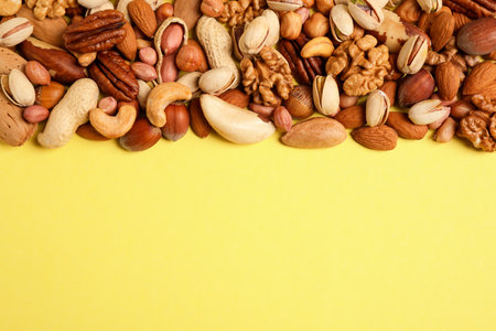 Different delicious nuts on yellow background, flat lay. Space for textの写真素材
