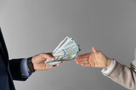 Man giving bribe money to woman on gray background, closeup