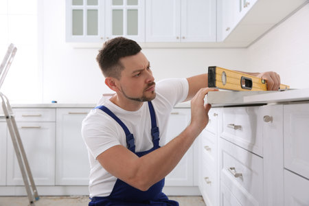 Worker measuring countertop with spirit level in kitchenの写真素材