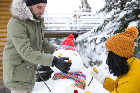 Happy couple making snowman outdoors. winter holidaysの写真素材