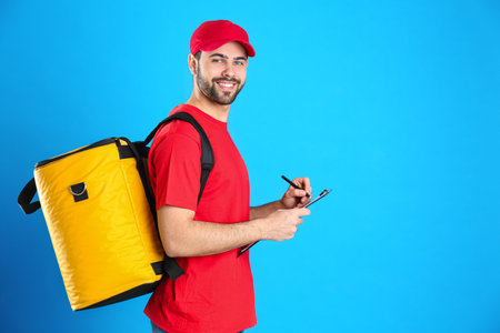 Courier with thermo bag and clipboard on light blue background, space for text. food delivery...
