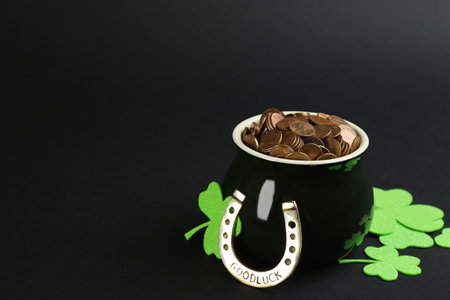 Pot of gold coins, horseshoe and clover leaves on black background, space for text. St. Patrick's Day celebrationの写真素材