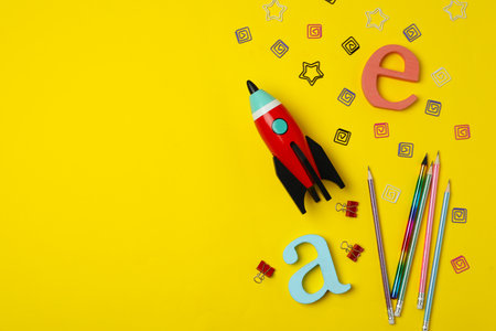 Bright toy rocket and school supplies on yellow background, flat lay. Space for textの写真素材
