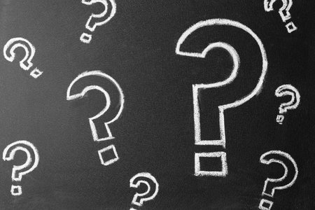 Question marks drawn with chalk on blackboard, top viewの写真素材